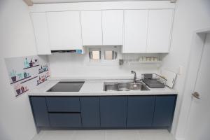 cocina con armarios blancos y fregadero azul en Hospitable House, en Seogwipo
