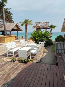 Amity Beach Resort في كوه ساموي: سطح خشبي مع كراسي بيضاء على الشاطئ