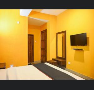 a yellow room with a bed and a flat screen tv at Hotel Stay Comfort inn in Gangtok