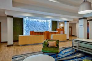 a lobby with a green chair and a counter at Fairfield Inn & Suites by Marriott Greenwood in Greenwood