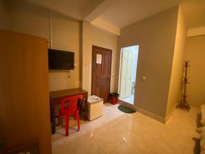 a room with a red chair and a desk and a television at The Grey Guesthouse in Phnom Penh