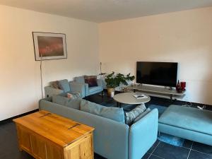 a living room with blue couches and a tv at Woning met 4 slaapkamers in Zelzate