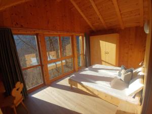 a bedroom with a bed in a cabin with windows at Unterplattnerhof in Chiusa