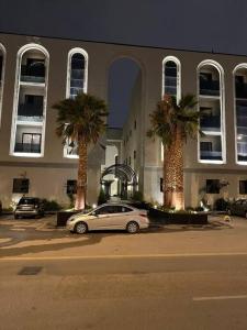 a car parked in front of a building with palm trees at شقة مودرن 3غرف نوم وصاله بالملقا c in Riyadh