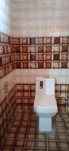 a bathroom with a toilet and a tiled wall at OYO Shiv guru guest house in Bodh Gaya
