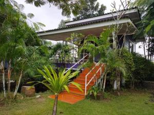 an orange staircase leading to a house with palm trees at อุดมทรัพย์วิลเลจฟาร์ม in Ban Huai Nam Khem