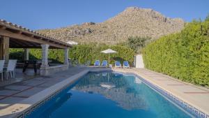 a swimming pool with chairs and a table with a mountain at Villa Cal Peso in Port de Pollensa