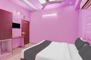 - une chambre rose avec un lit et une télévision dans l'établissement Collection O Hotel Raj Palace, à Sātej