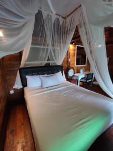 een slaapkamer met een wit bed en een baldakijn bij Umajero Hut in Silebeng