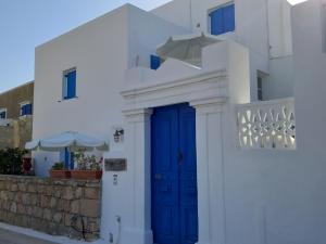 - un bâtiment blanc avec une porte bleue et un parasol dans l'établissement Angelica, à Frý