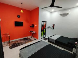 um quarto com paredes cor-de-laranja, uma cama e uma televisão. em Roomstay Kak Ton em Kuala Terengganu