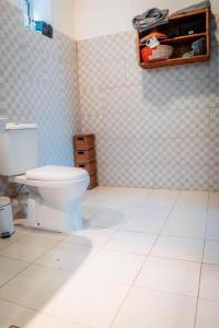 a bathroom with a toilet and a tiled floor at Hibiscus House Gambia in Brufut