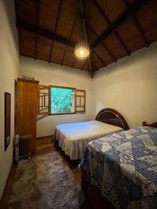 a bedroom with two beds and a window at Encanto Chalé in Monte Verde