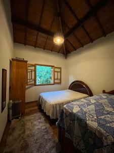 a bedroom with two beds and a window at Encanto Chalé in Monte Verde
