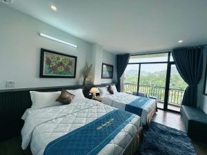 a hotel room with two beds and a balcony at Trang An Legend in Ninh Binh