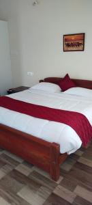 a bedroom with a large bed with white and red sheets at Sri Lakshmi Estates in Siddapur