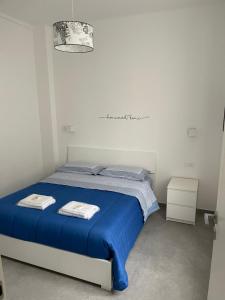 a bed in a white room with a blue blanket at Deluxe Apartment Self Check in Parking in Genova