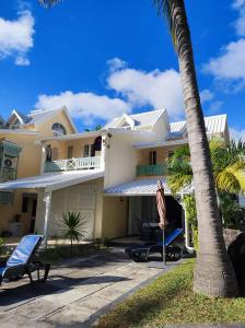 ein Haus mit einer Palme und zwei Stühlen in der Unterkunft 23 Residence Thalassa, in Belle Mare
