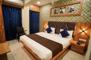 a bedroom with a large bed with blue pillows at Hotel Mahaveer in Ahmedabad