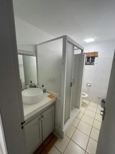 La salle de bains blanche est pourvue d'un lavabo et d'une douche. dans l'établissement 23 Residence Thalassa,, à Belle Mare