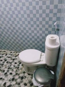 a bathroom with a toilet in a tiled wall at Bungalow Pandan Dure in Selong