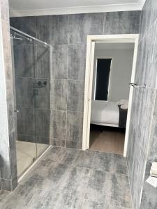 een badkamer met een douche en een slaapkamer met een bed bij Townhouse in West Footscray in Seddon
