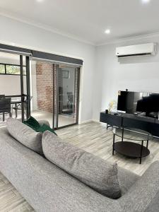 uma sala de estar com um sofá e uma televisão em Townhouse in West Footscray em Seddon