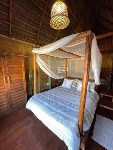 a bedroom with a canopy bed in a cabin at Cheerful 3-bedroom holiday beach cabin. in Inhambane