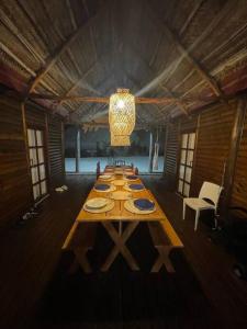 a long wooden table in a room with a chandelier at Cheerful 3-bedroom holiday beach cabin. in Inhambane
