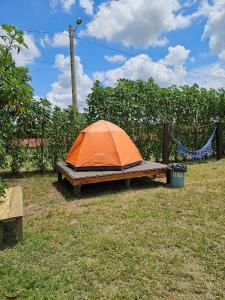 an orange tent sitting in the grass next to a fence at Santa Filomena Camping in Descalvado