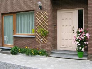 uma casa com uma porta branca e algumas flores em Liry's Home em Tongeren