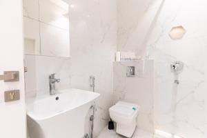 a white bathroom with a sink and a toilet at Amber Hospitality - Al Qairawan in Riyadh