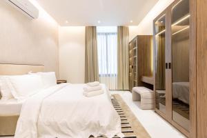 a bedroom with a white bed and a walk in closet at Amber Hospitality - Al Qairawan in Riyadh
