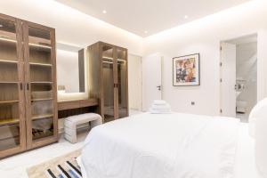 a white bedroom with a large bed and a bathroom at Amber Hospitality - Al Qairawan in Riyadh