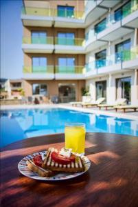 un plato de comida y una bebida en una mesa junto a una piscina en Crystal Bay Hotel en Kíssamos