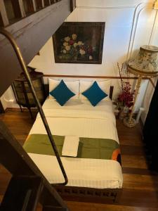 een slaapkamer met een bed met blauwe en groene kussens bij 103 - Bed and Brews in Bangkok