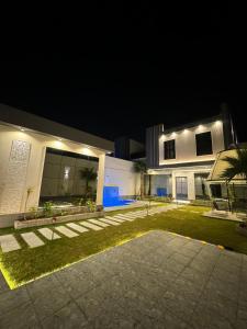 uma casa à noite com luzes ao lado em شاليه الرتاج الفندقي em Buraydah