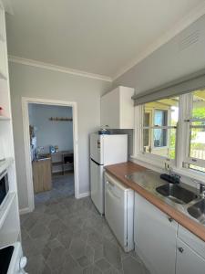 a kitchen with a white refrigerator and a sink at Cottage 32 in Lakes Entrance +15 photos