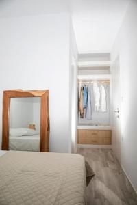 a white bedroom with a bed and a mirror at White Nadora Naxos Villa in Agia Anna Naxos