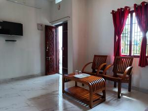 a living room with two chairs and a table and a television at Rudra Villas in Rāmeswaram