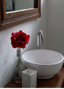 uma rosa vermelha num vaso ao lado de um lavatório em LE BOUTIQUE SUÍTES - PRAIA de MARESIAS em Maresias