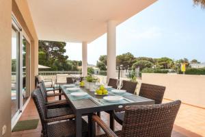 Une table à manger et des chaises sont disponibles sur la terrasse. dans l'établissement Villa Victoria Paradise, à Cala en Blanes