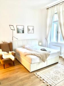 a white bedroom with a bed and a chair at BRANDNEW - Executive Apartement 1 in Bad Gastein