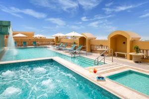 uma piscina em um resort com cadeiras e uma fonte em Somerset Al Mansoura Doha em Doha
