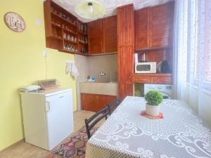 a small kitchen with a table and a refrigerator at Апартамент Панорама Трявна - кът за отдих, въздухолечение и почивка in Tryavna