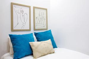 - un canapé blanc avec des oreillers bleus et 2 photos dans l'établissement Oporto Cosy Apartment, à Porto