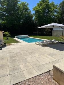 einen Pool mit Stühlen und einem Sonnenschirm in der Unterkunft Villa de vacances avec piscine privative chauffée in Saint-Maime