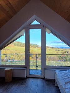 una camera da letto con ampie finestre con vista su un campo di Domek na Wielkiej Górze a Waksmund