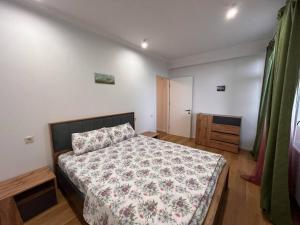 a bedroom with a bed with a floral bedspread at Cosy Apartment in Varketili in Samgori