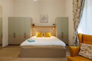 a bedroom with a bed with yellow pillows and a chair at Victoriei Square Apartment in Timişoara